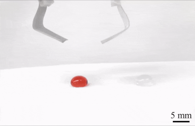 an animated image showing pincers descending from the top of the image to grab a small red drop of liquid, after picking the liquid up by sliding the ends of the pincers under the liquid, the droplet is dropped on top of a clear droplet nearby
